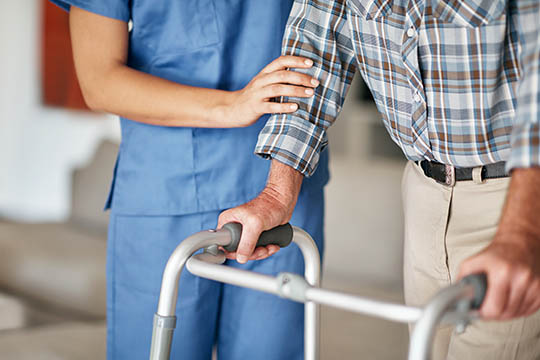 Healthcare professional assisting an elderly man with a walker, representing AdvisaCare's commitment to helping patients maintain independence thorough comprehensive home care services